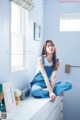 A woman sitting on top of a white dresser next to a window.