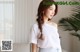 a woman standing in front of a couch wearing a white top