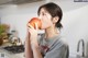 A woman is eating an apple in the kitchen.