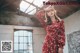 A woman in a red dress standing in an abandoned building.