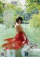 A woman in a red dress standing in the water.