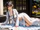 A woman in a white kimono laying on a wooden floor.