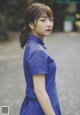 A woman in a blue dress standing on a street.