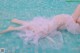 A woman in a pink dress laying on the edge of a pool.