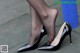 A close up of a woman's legs wearing black high heels.