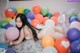 A woman laying on a bed surrounded by balloons.