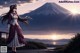 A woman in a long dress standing in front of a mountain.